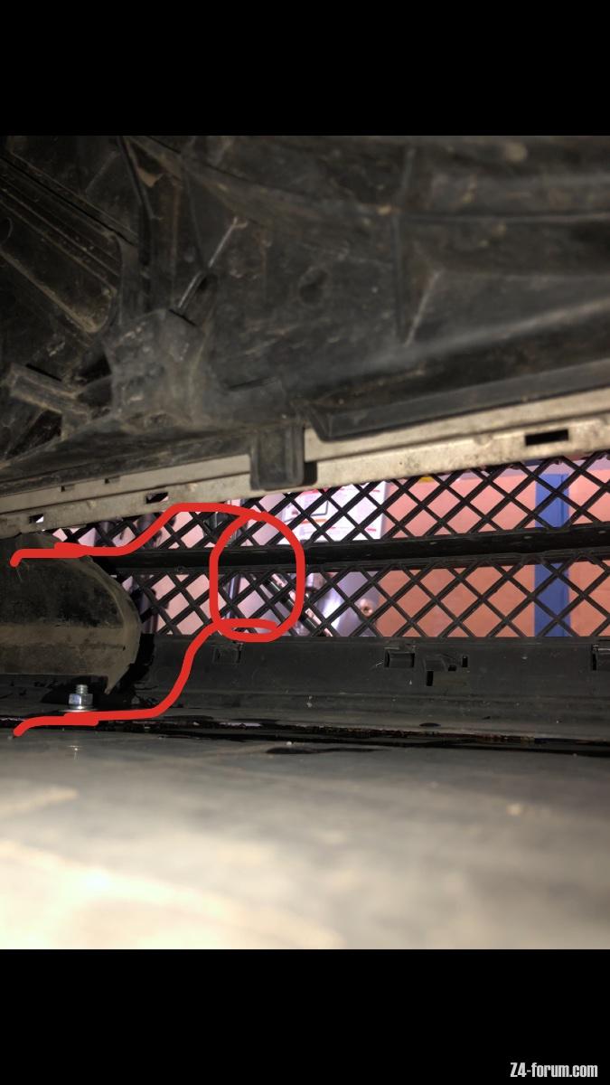 The tube will travel in a straight path to here where it will pass under the radiator, either on the right side of the rubber flap or through it, whichever one avoids the radiator plug.
